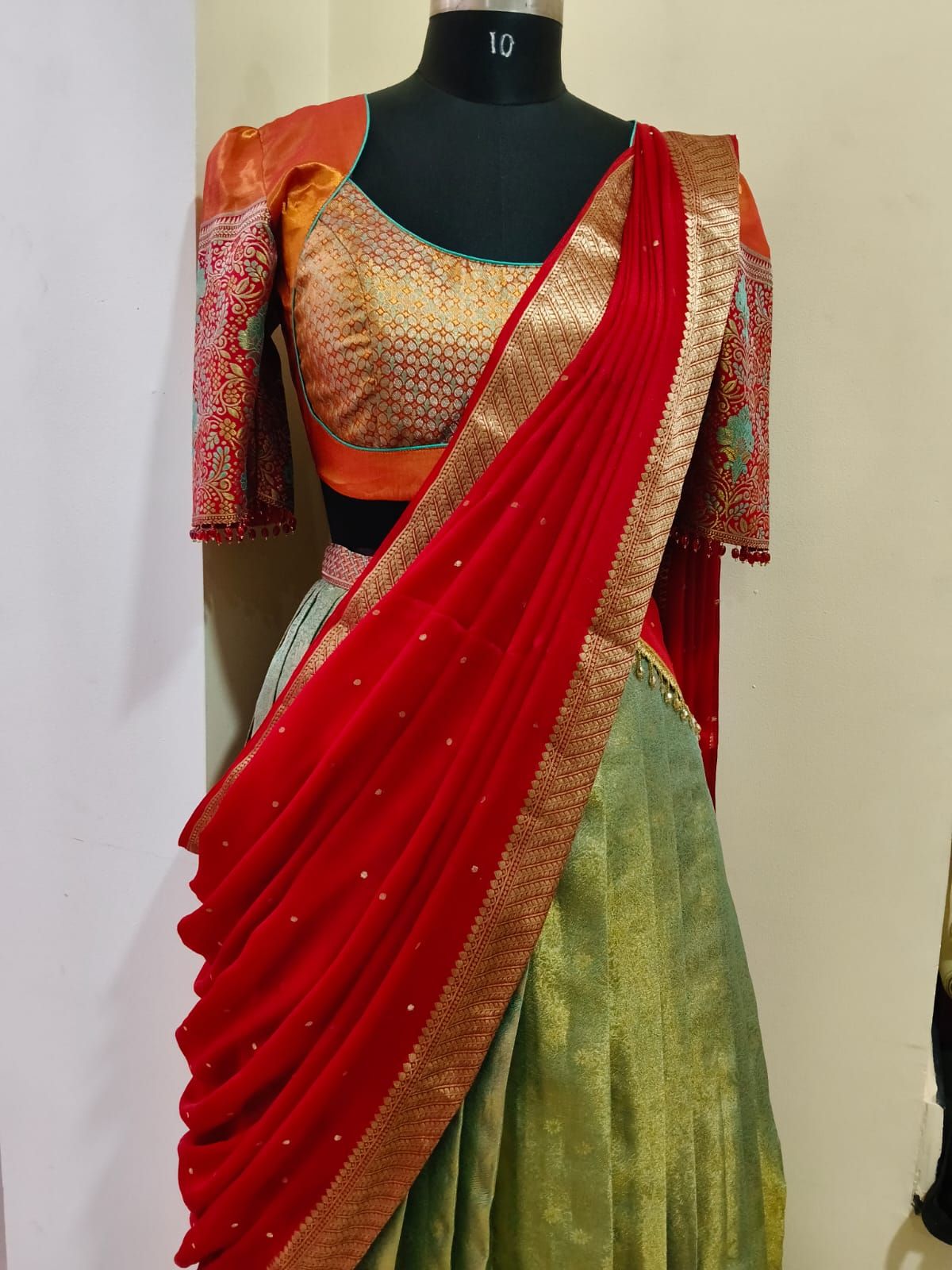Half-saree with a red dupatta pleated over an orange brocade blouse and green skirt