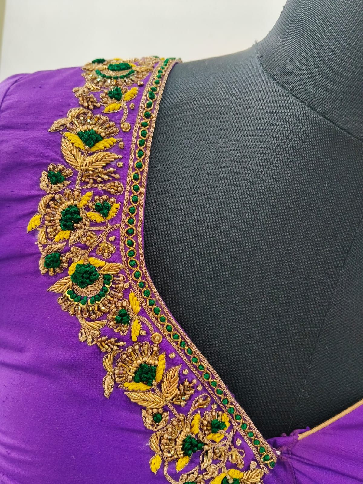 Gold, green and yellow aari florets along a violet neckline