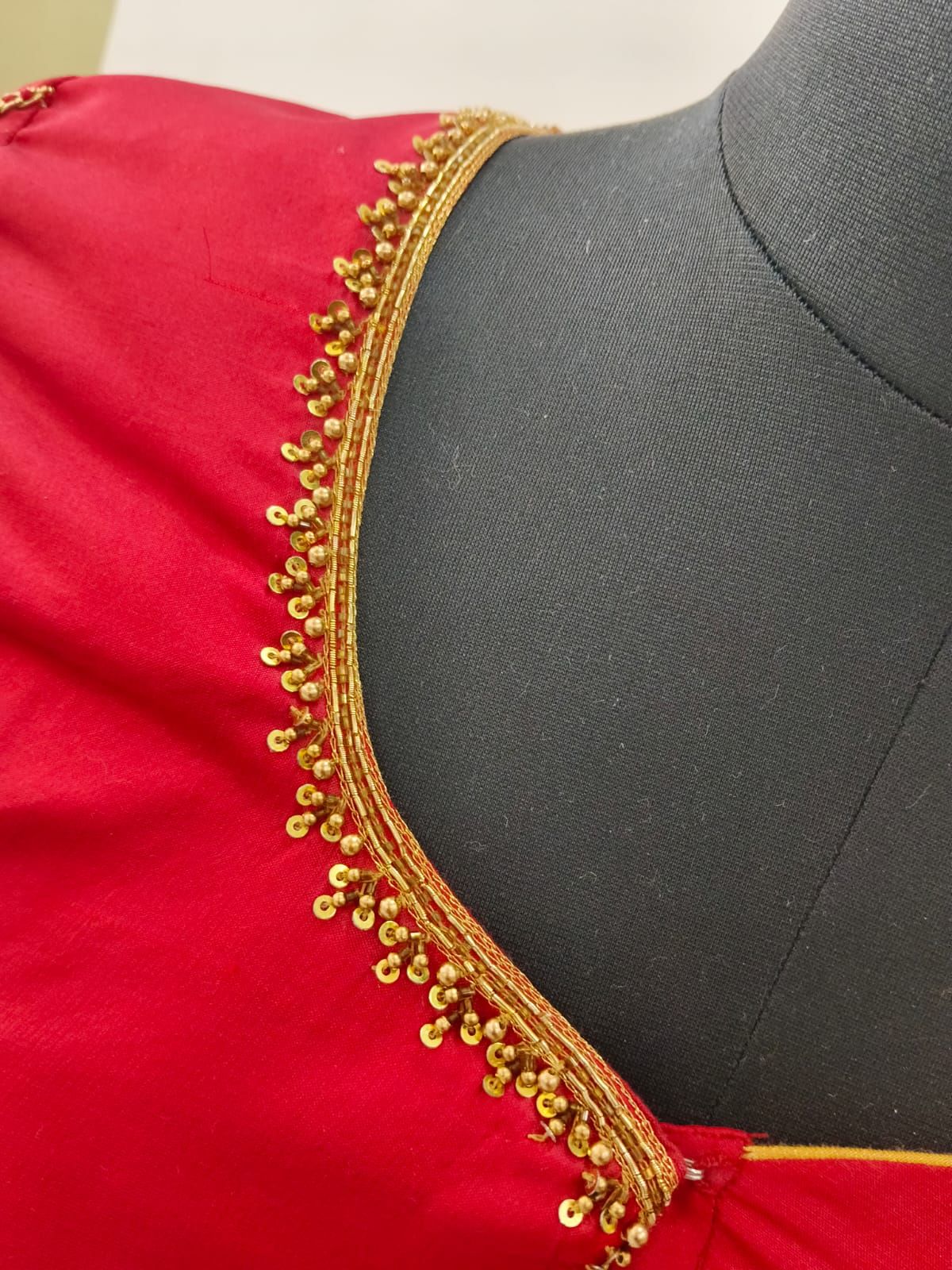 Fine gold bead and sequin edging on a red neckline