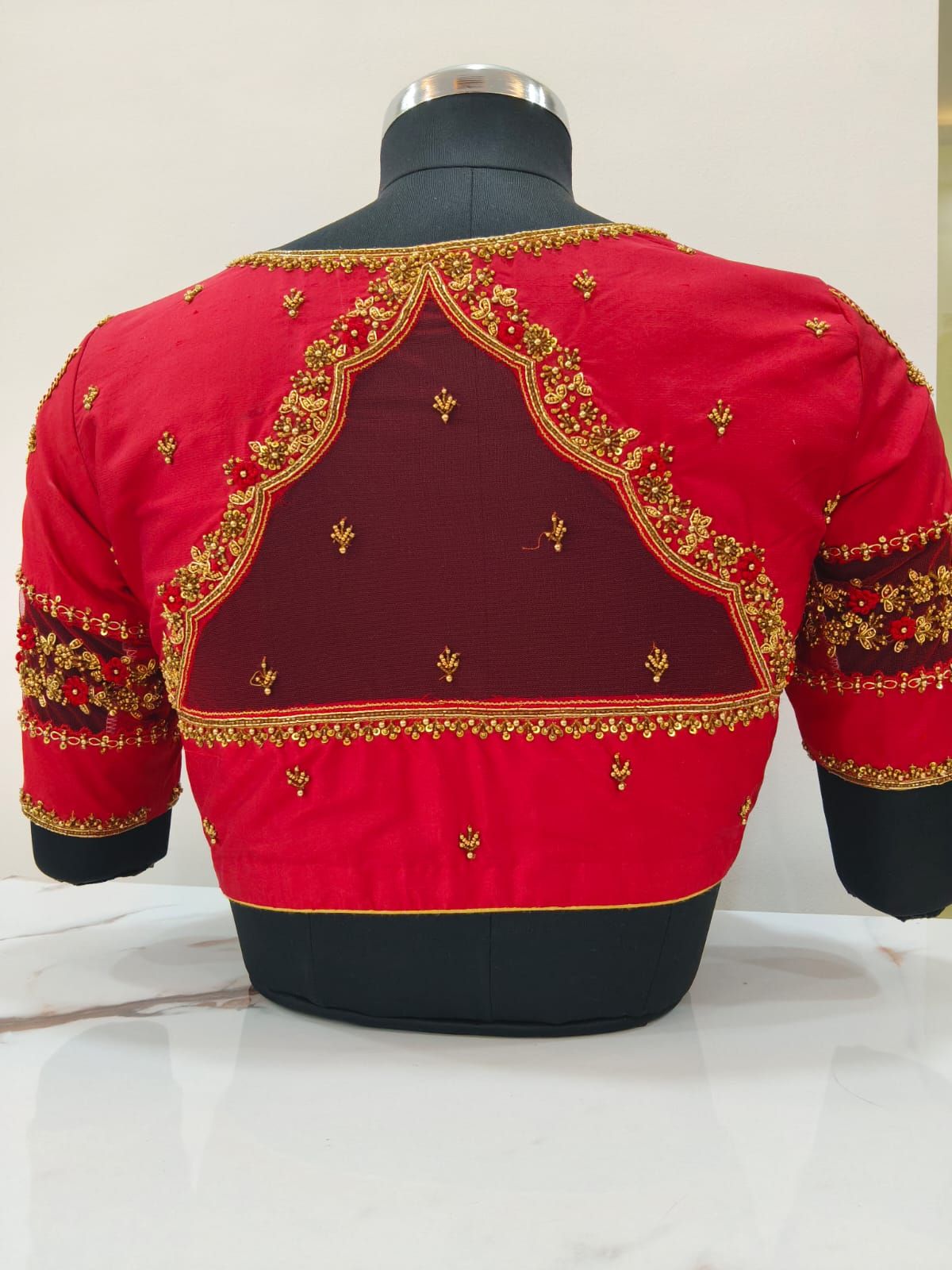 Red bridal blouse from the back with a sheer net panel and scalloped gold embroidery
